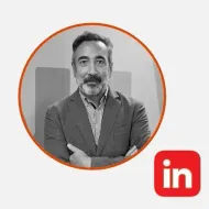 Hombre con blazer, brazos cruzados y sonriendo. Foto de perfil de LinkedIn.